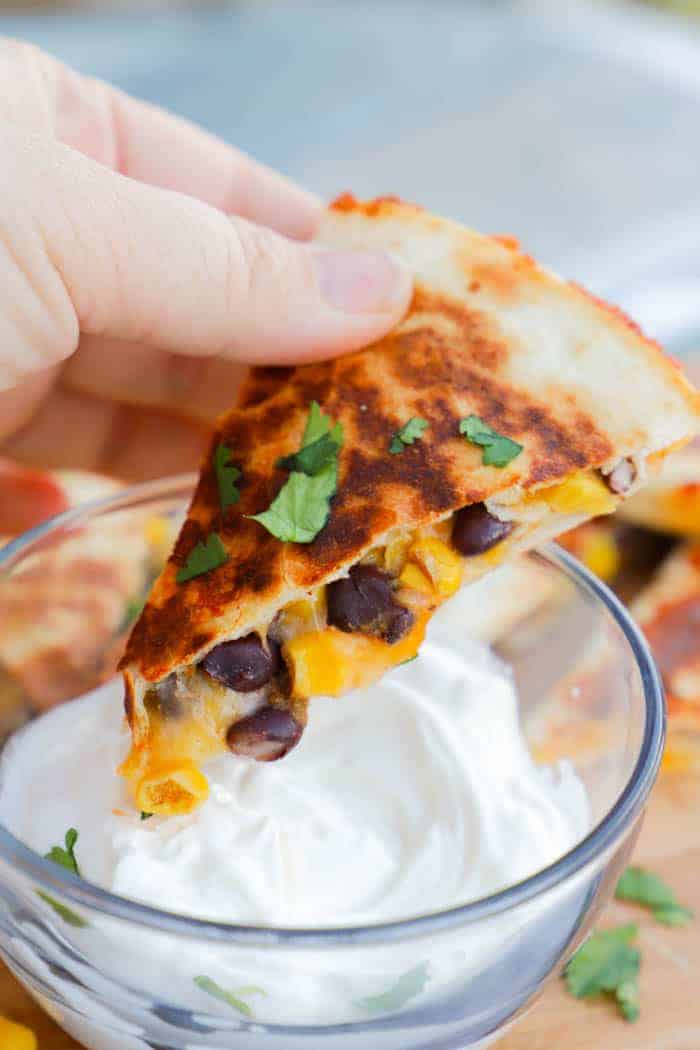 Black Bean and Cheese Quesadillas dipping in sour cream.
