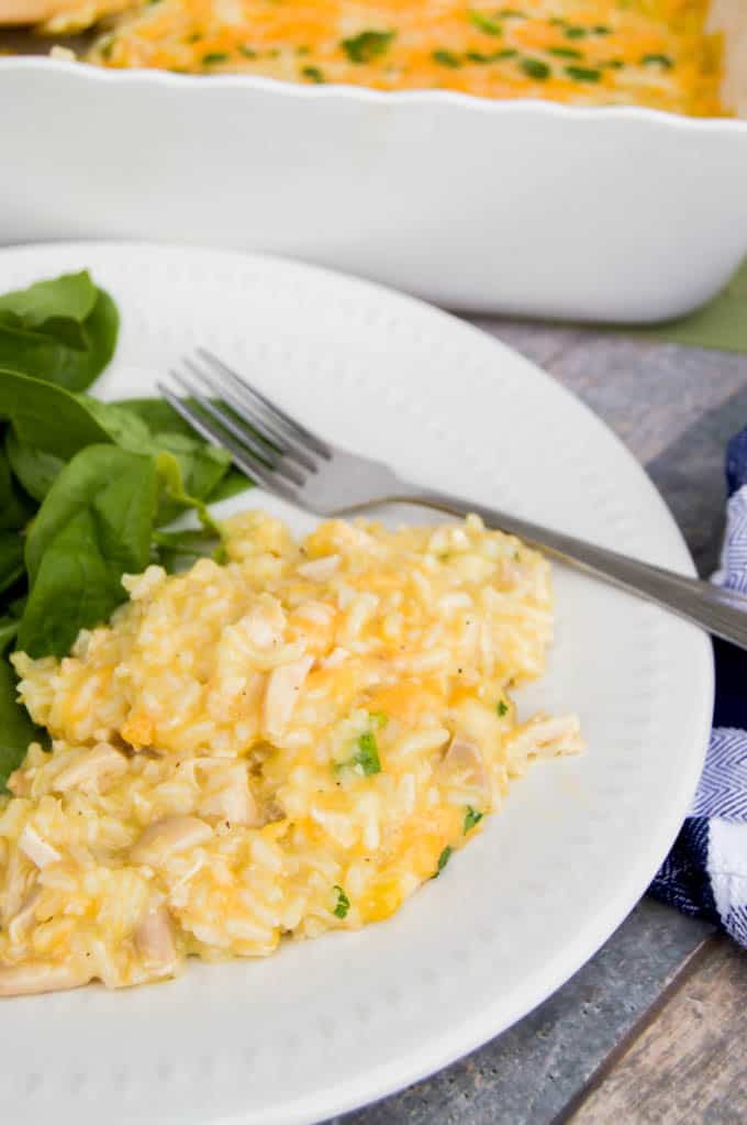 chicken and rice casserole on a white plate with salad