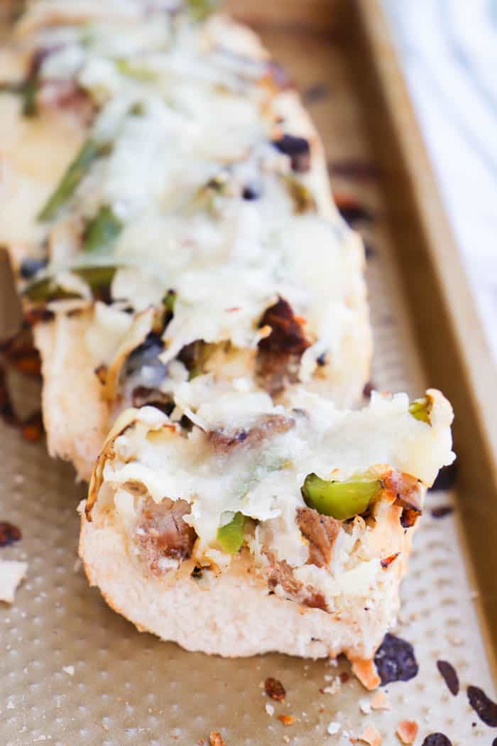 Philly Cheese Steak French Bread Pizza sliced on a baking sheet