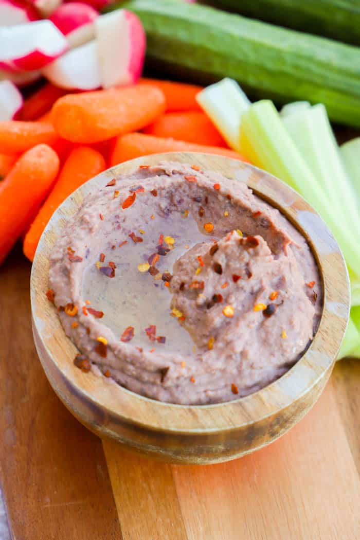 Black Bean Hummus in wooden bowl with veggies around it