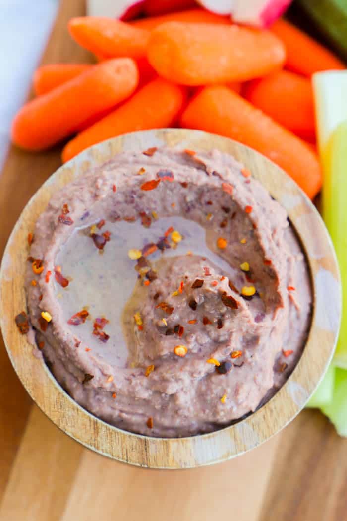 close up of black bean hummus in wooden bowl with veggies