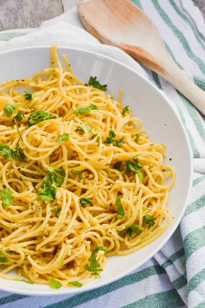 5 Ingredient Parmesan Garlic Spaghetti in a white bowl with wooden spoon