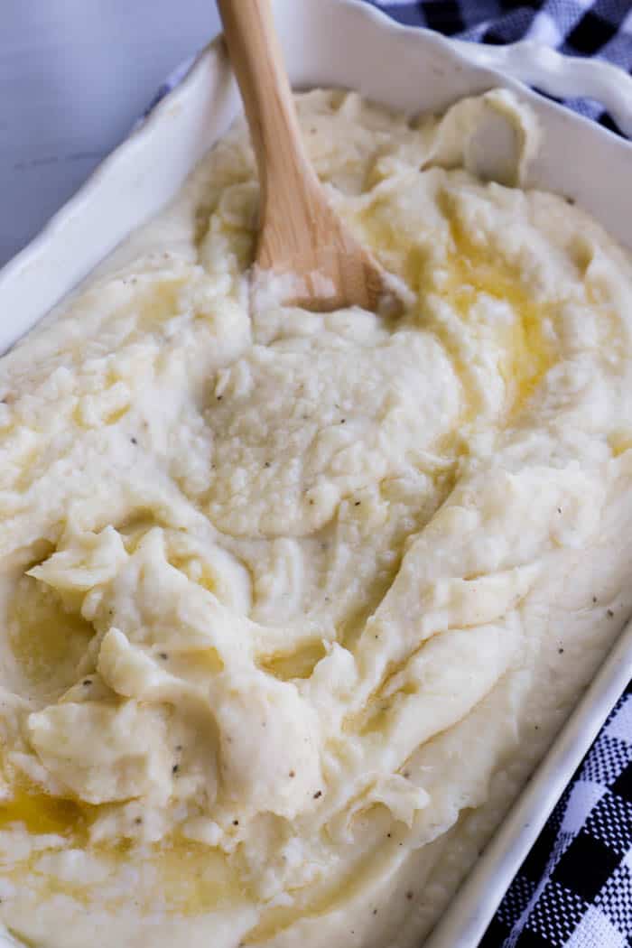 mashed potatoes in a casserole dish with wooden spoon sat inside