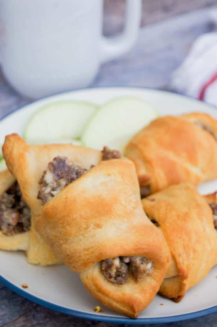 Cream Cheese Sausage Crescent Roll Ups on plate with apple slices