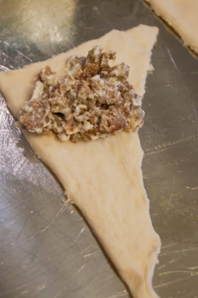 adding sausage mixture to crescent roll dough