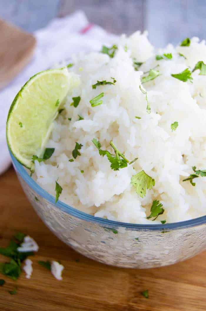 Cilantro Lime Rice closeup in clear bowl with cilantro and lime on top