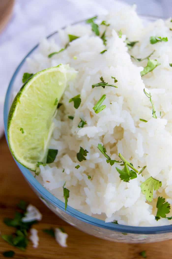 Cilantro Lime Rice closeup in clear bowl with cilantro and lime on top
