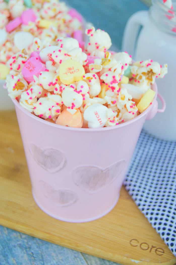 White Chocolate Valentine's Day Popcorn in pink pail on wooden board