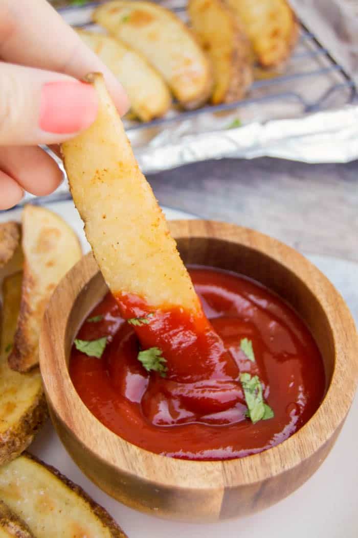 dipping potato wedge into ketchup.