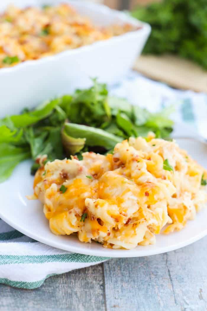 Chicken Bacon Ranch Casserole on white plate with salad, casserole dish in background