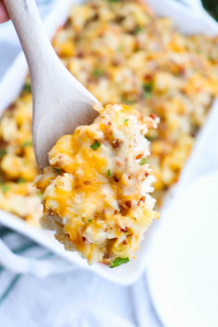 Chicken Bacon Ranch Casserole on wooden spoon scooped out of white casserole dish