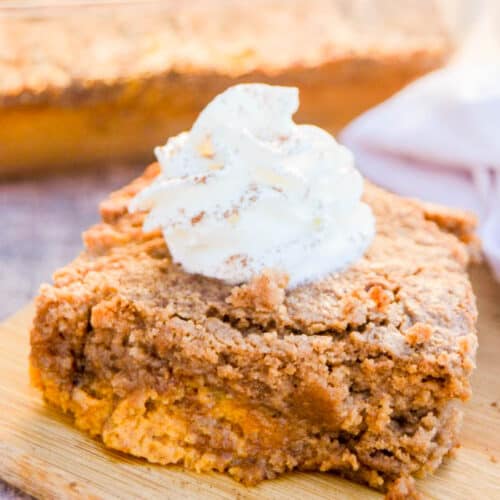 Pumpkin Spice Dump Cake on a cutting board with whipped cream