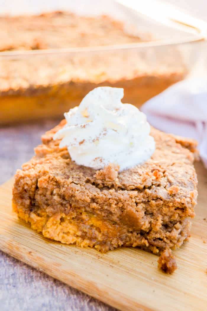 Pumpkin Spice Dump Cake on a cutting board with whipped cream