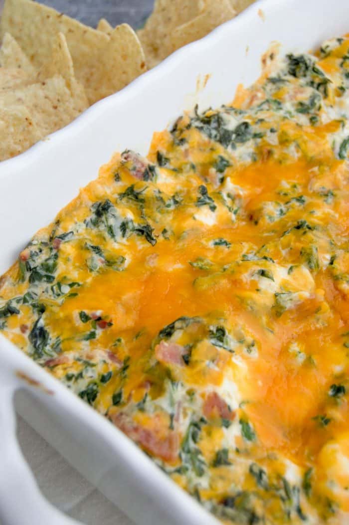 Cheesy Bacon Spinach Dip in a white dish with chips