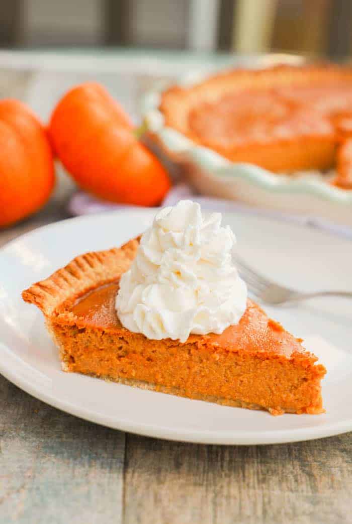 Easy 5 Ingredient Pumpkin Pie on white plate with whipped cream.