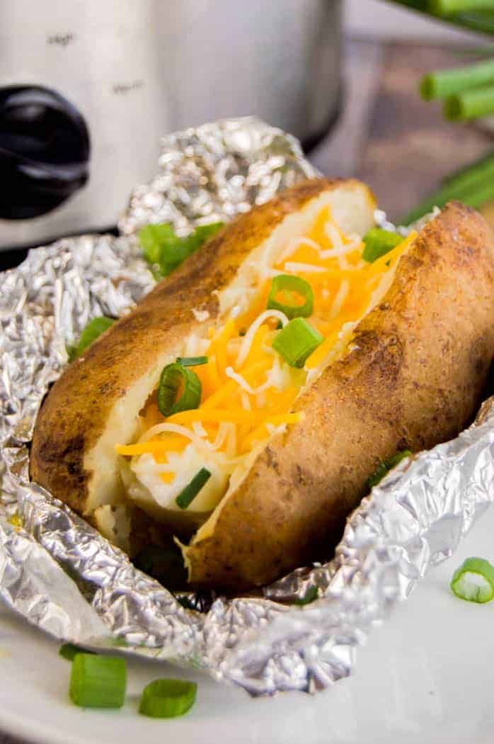 Slow Cooker Baked Potatoes split and topped with cheese and green onions