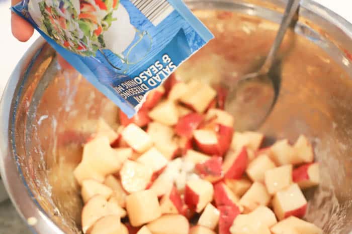 adding ranch seasoning to the bowl for Slow Cooker Cheesy Ranch Potatoes 