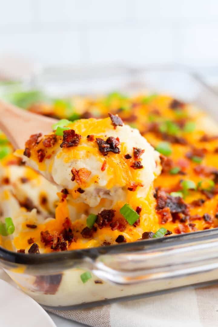 closeup of loaded mashed potatoes scooped on wooden spoon.