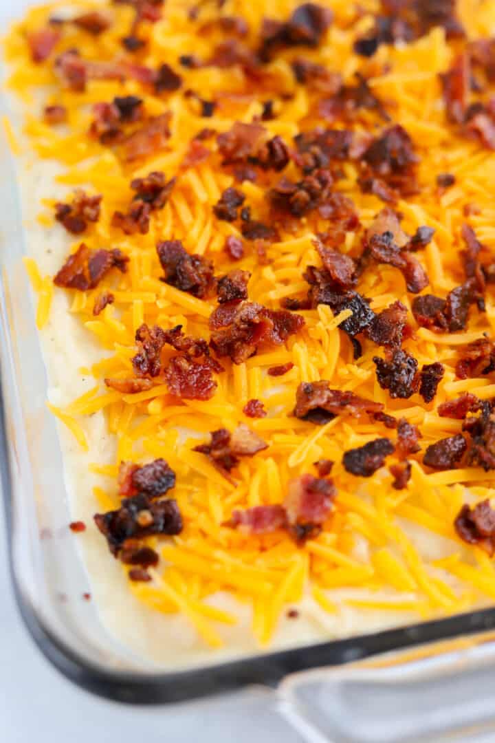 closeup of mashed potatoes with cheese and bacon on top.
