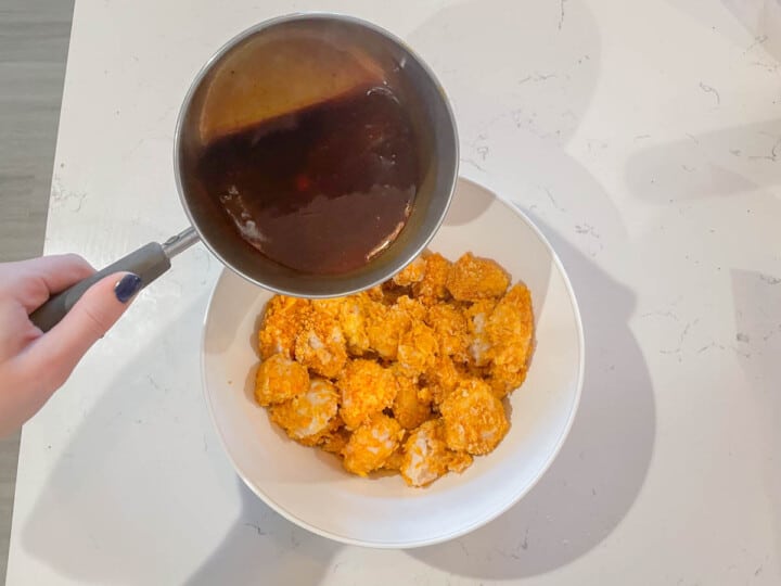 Pouring the honey BBQ sauce over the chicken bites