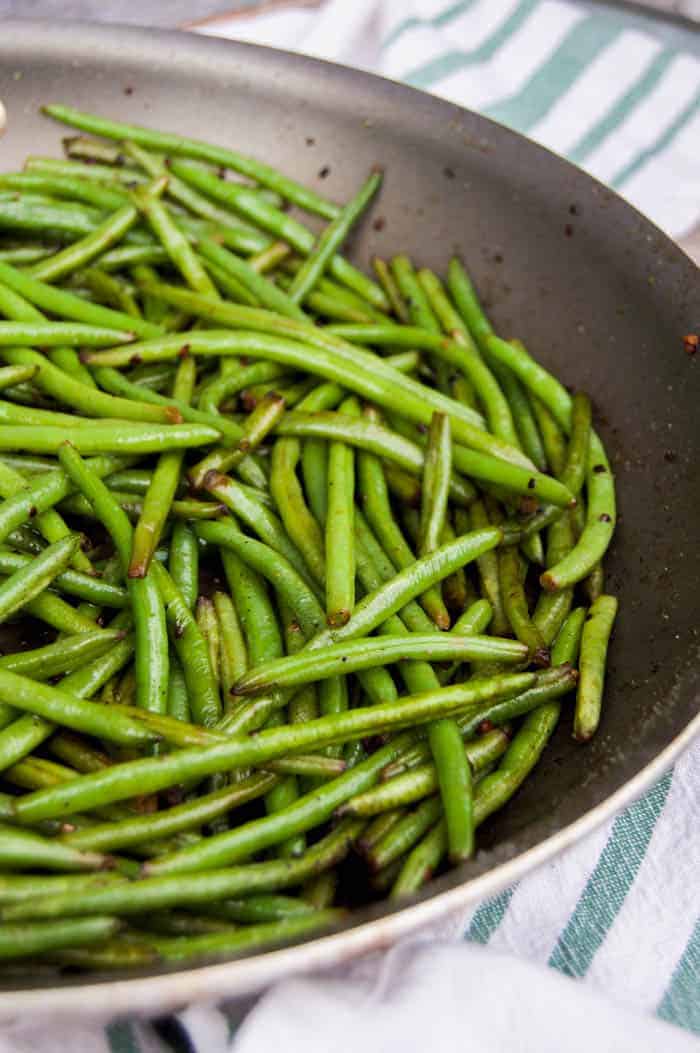 Closeup shot of green beans in skillet on white and green cloth