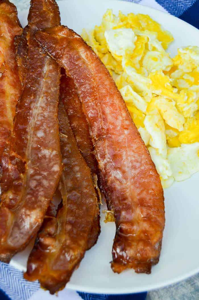 Oven Baked Bacon on white plate with scrambled eggs