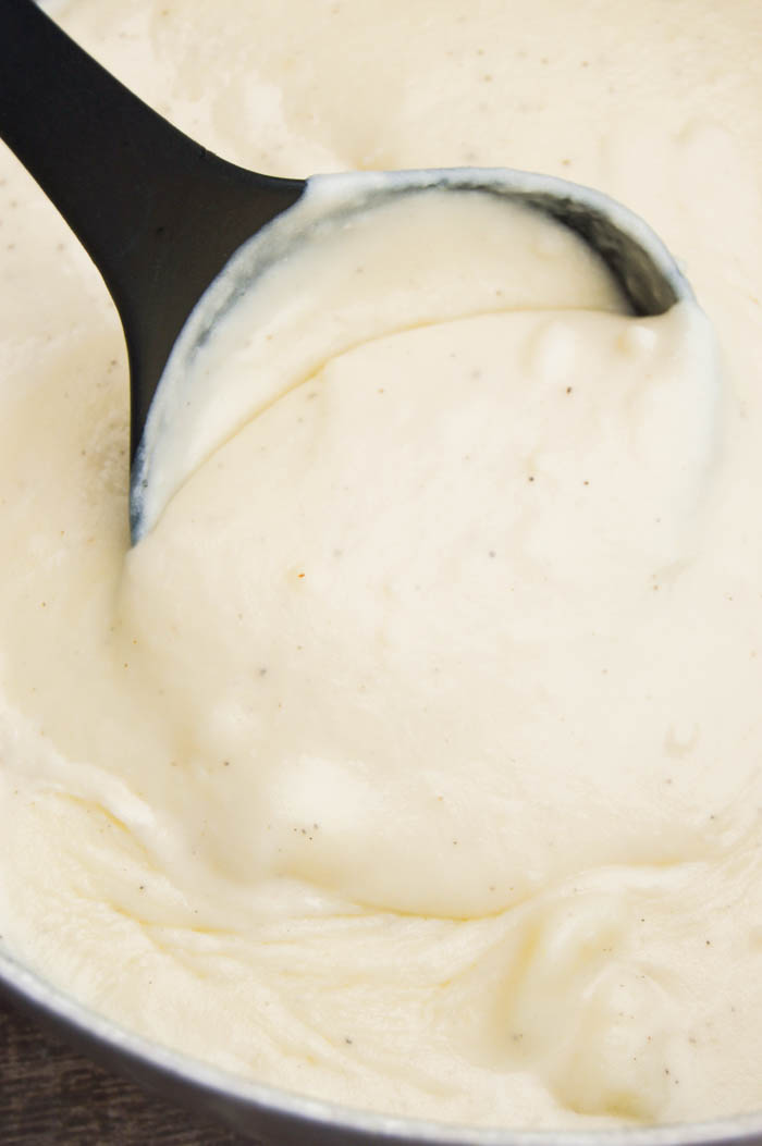 Close up shot of potato soup in pot, scooped out with black spoon