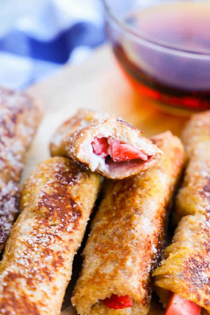 Strawberry French Toast Roll Up closeup with syrup in the background.