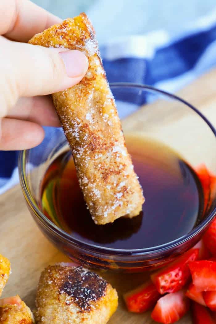 Strawberry French Toast Roll Up dipped into bowl of syrup.