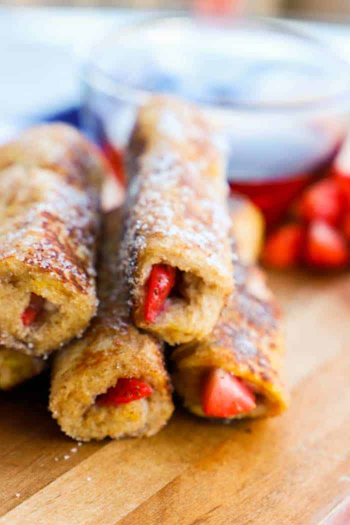 Strawberry French Toast Roll Up closeup with syrup in the background.