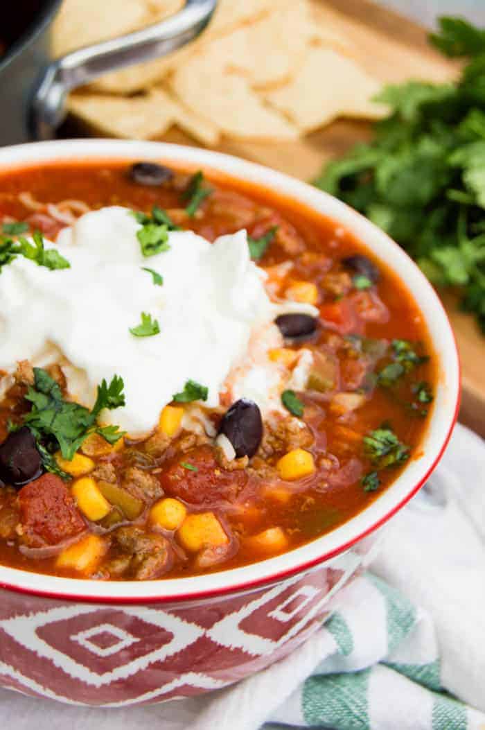 Taco soup in red bowl in towel