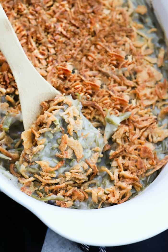 Green Bean Casserole being scooped out with a wooden spoon