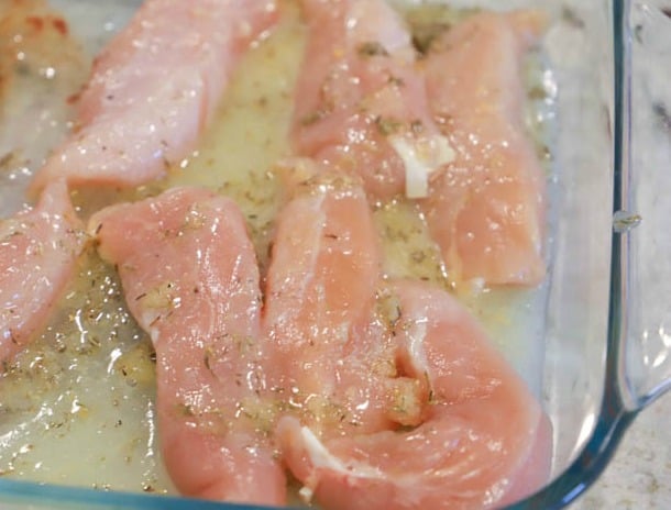 adding seasoned chicken to a casserole dish