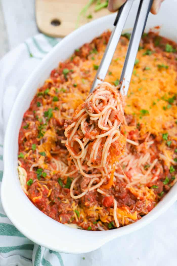 Spaghetti Casserole being scooped out of the dish with tongs.