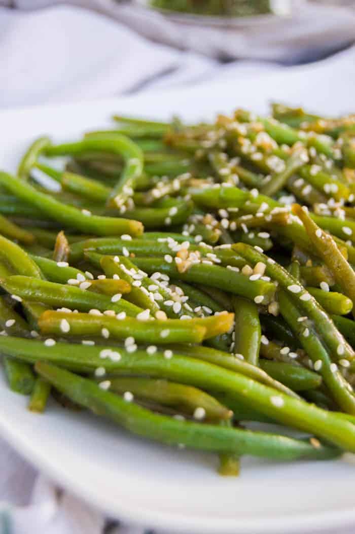 Garlic Asian Green Beans on white plate with sesame seeds on top