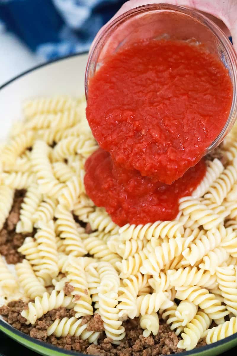 adding salsa to cooked noodles and ground beef