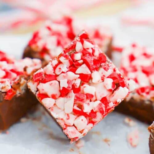 Fudge on a parchment paper with candy canes in back