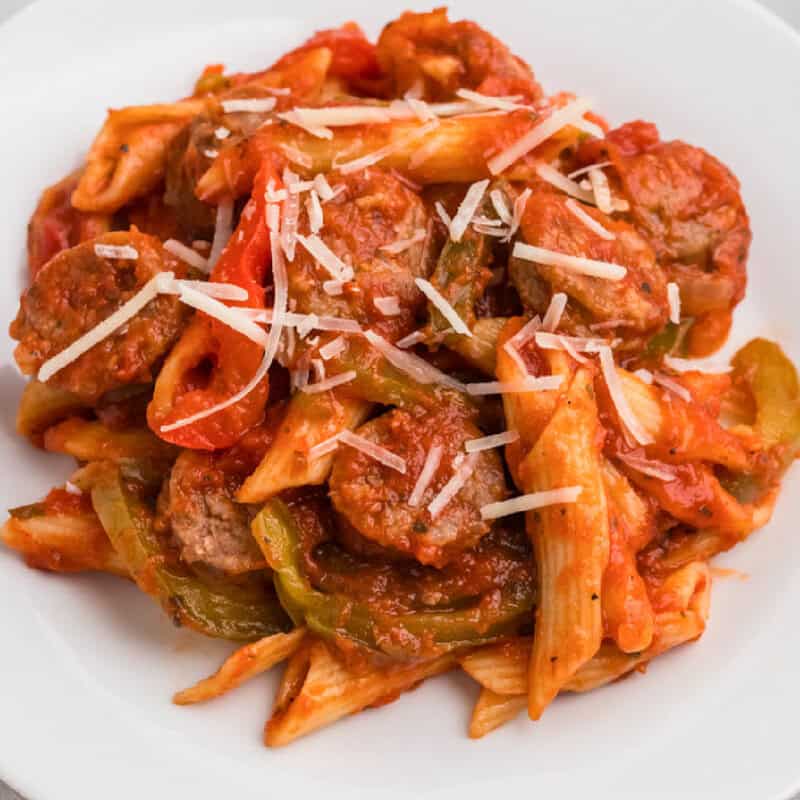 One-Pan Italian Sausage and Peppers Penne on a white plate topped with cheese