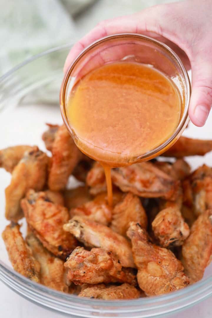 pouring the buffalo sauce on the wings.