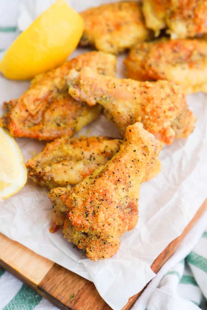 Crispy Baked Lemon Pepper Wings on parchment paper with lemons.