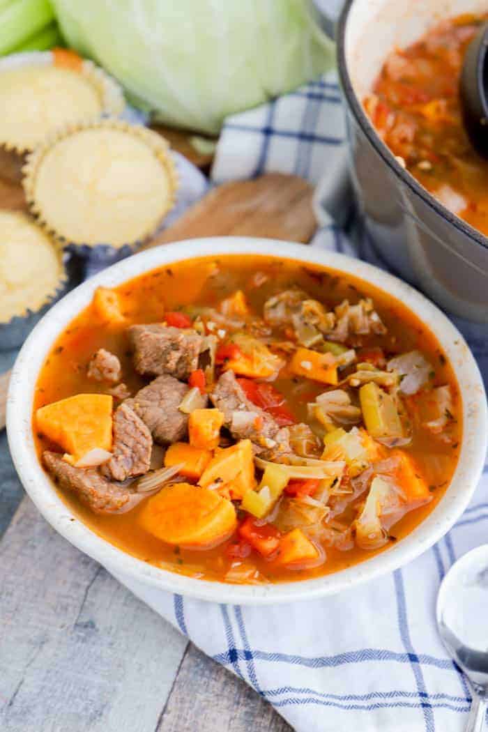 Sweet Potato Beef Stew in a white bowl with cornbread