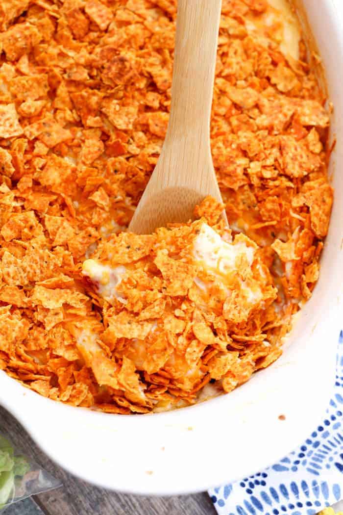 Dorito Chicken Casserole in white casserole dish with wooden spoon in it