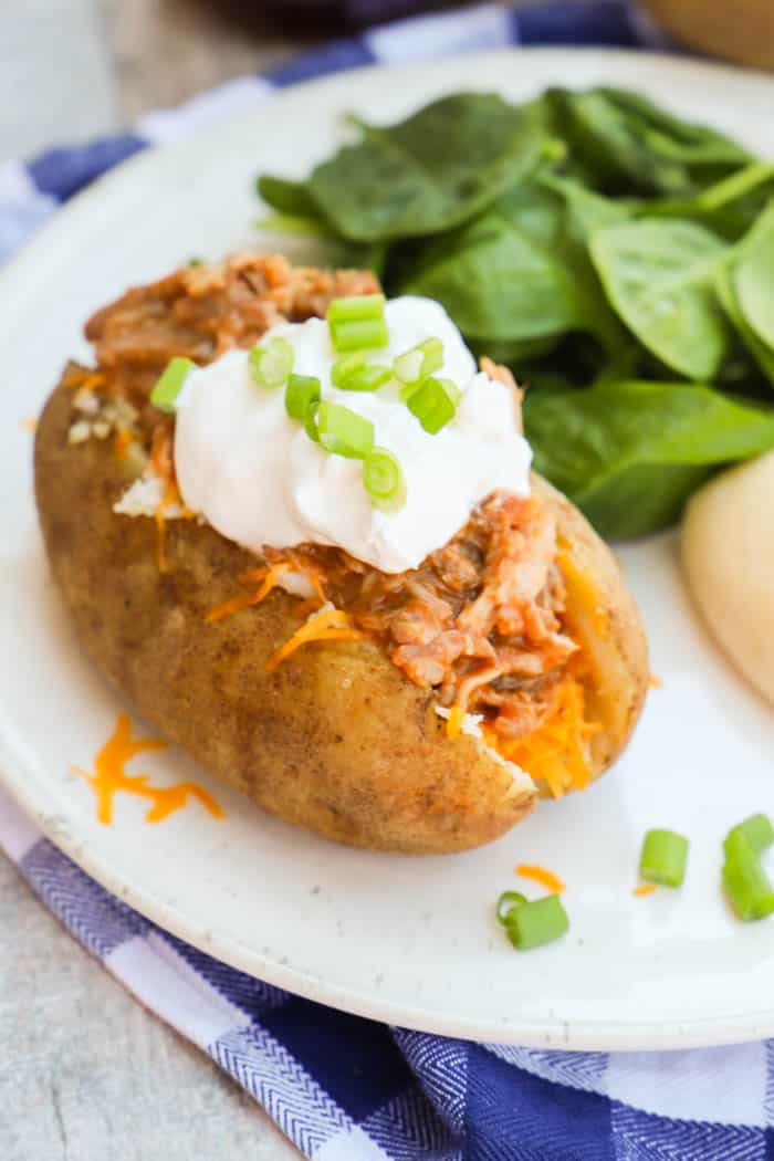 BBQ Pulled Pork Potato Skins on a white plate with salad