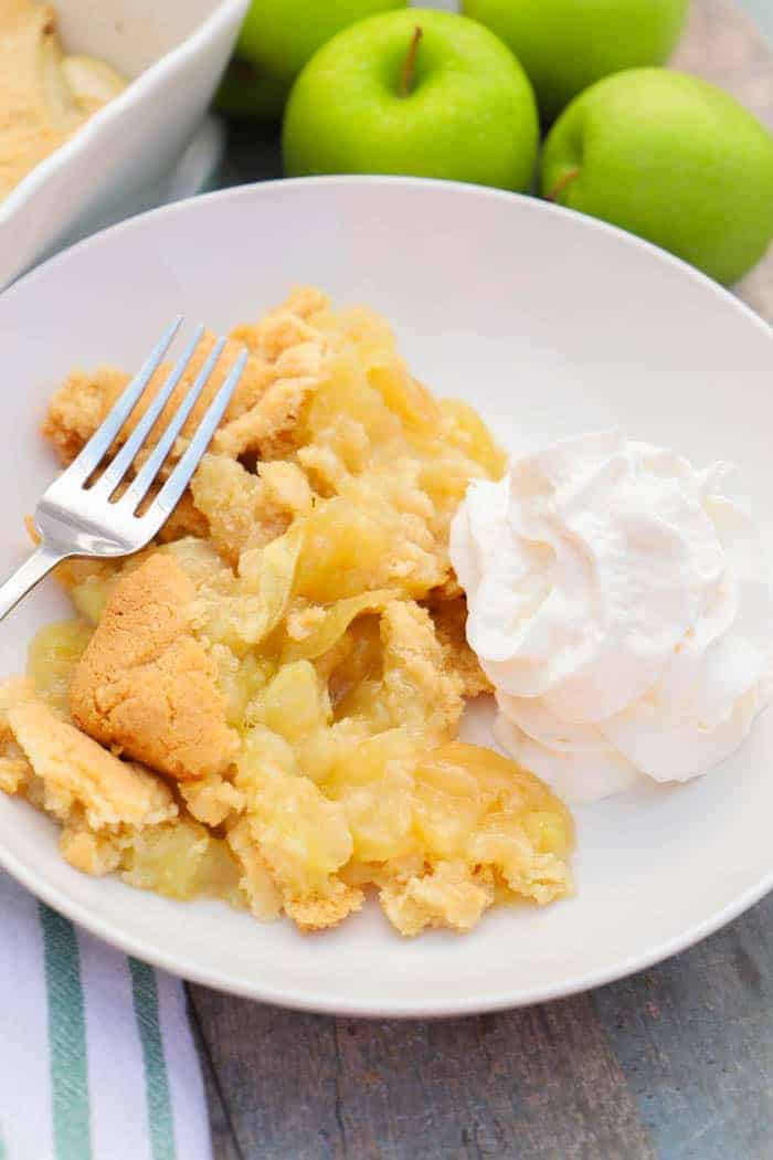 Apple Cobbler in a white plate with whipped cream.