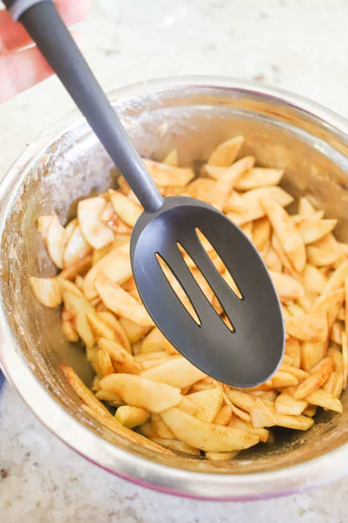 apples being scooped with a slotted spoon.