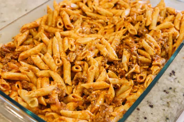 adding pasta to a casserole dish to bake