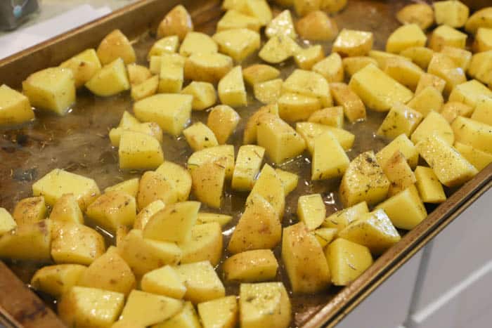 adding potatoes to the sheet pan