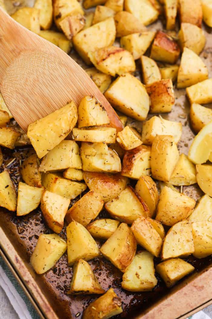 Lemon Herb Roasted Potatoes on a pan with a wooden spoon