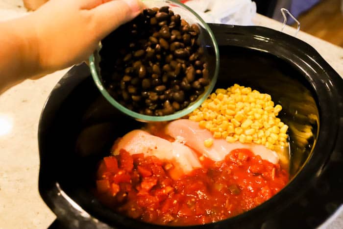 Slow Cooker Chicken Taco Soup adding ingredients to the slow cooker