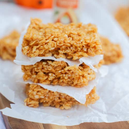 Pumpkin Spice Rice Krispies Treats stacked on a cutting board